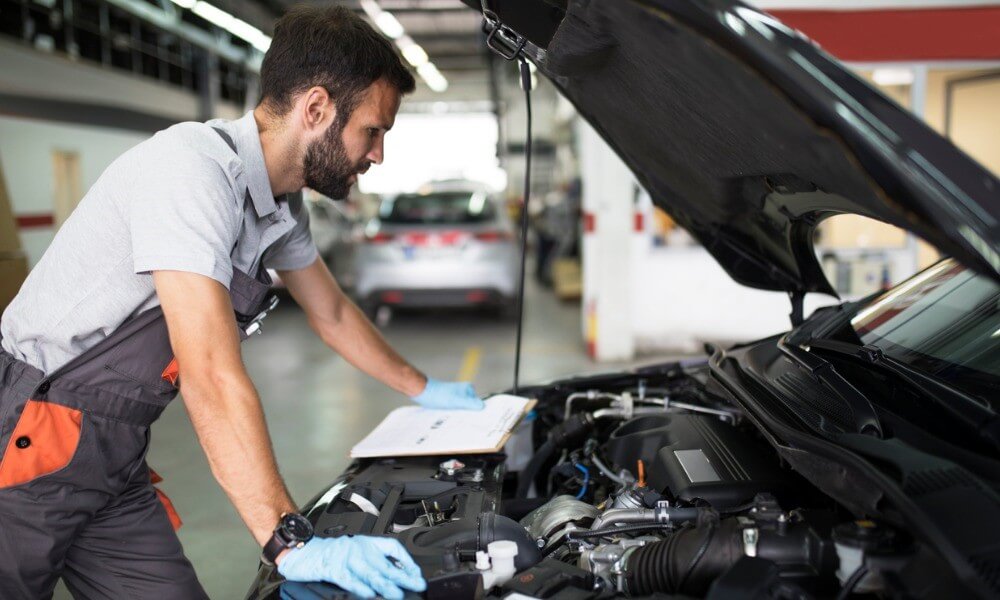 Mechaniker steht vor geöffneter Autohaube