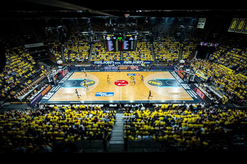 Weitaufnahme eines Basketball-Felds mit Publikum.