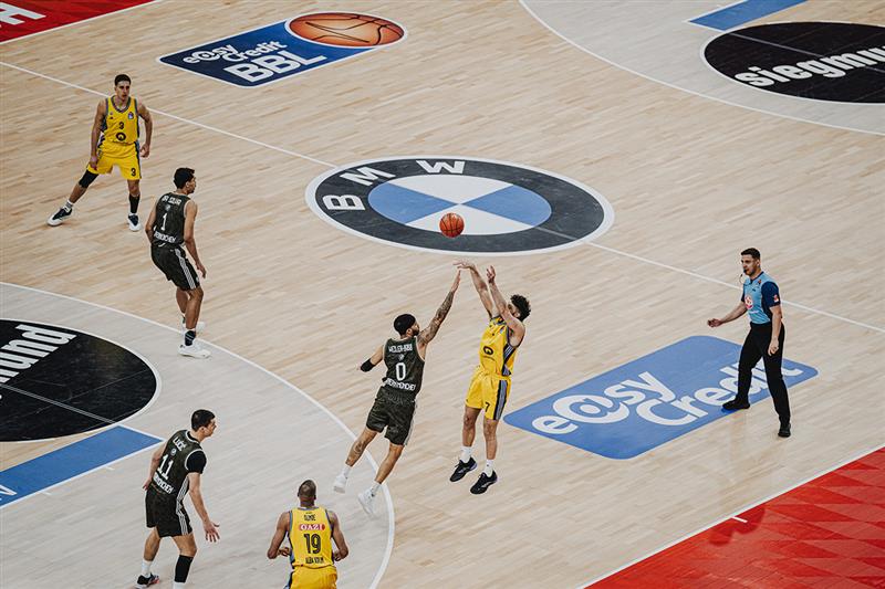 Aufnahme aus Bundes Baskeltball Liga Spiel. Zwei Spieler springen in die Luft um dem Ball zu fangen.