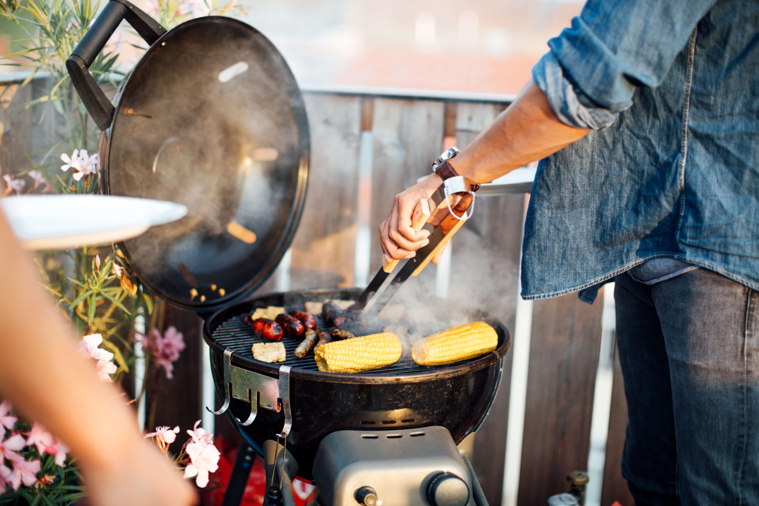 Ein erwachsener Mann grillt entspannt Gemüse auf seinem Balkon