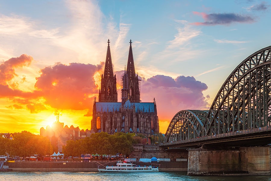Aufnahme von Köln bei Sonnenuntergang. Zu sehen sind der Rhein und rechts die Hohenzollernbrücke, die zum Dom führt.