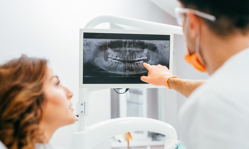 Ein Zahnarzt zeigt seiner Patientin ein Röntgenbild.
