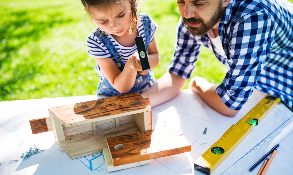 Papa und Tochter bauen ein Vogelhaus im Freien