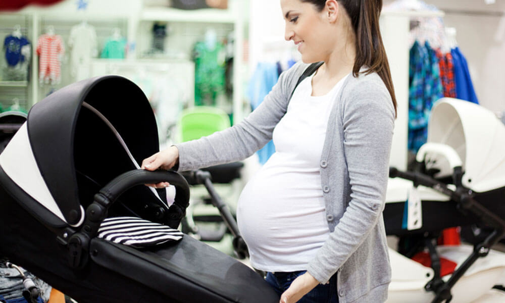 Eine schwangere Frau begutachtet im Fachgeschäft einen Kinderwagen.