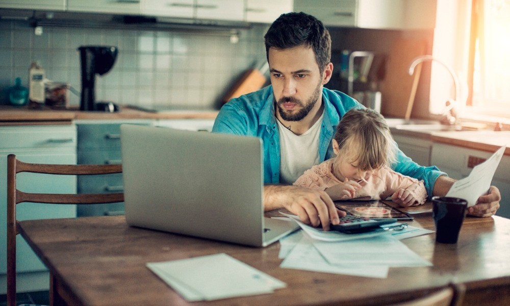 Papa und Kind sitzen gemeinsam am Tisch vor einem Laptop