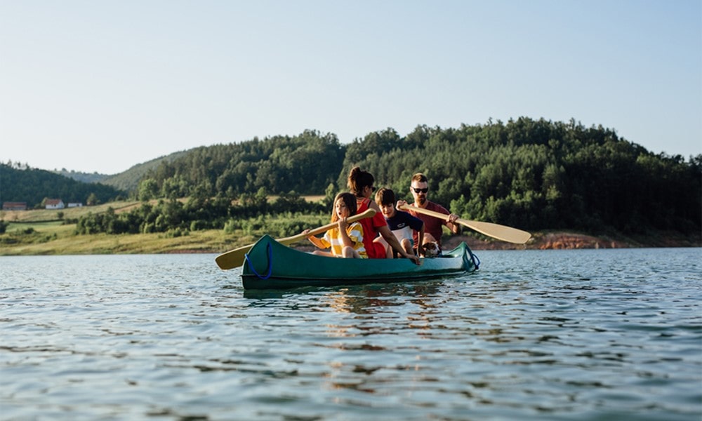 Eine Familie paddelt im Kanu über einen See.