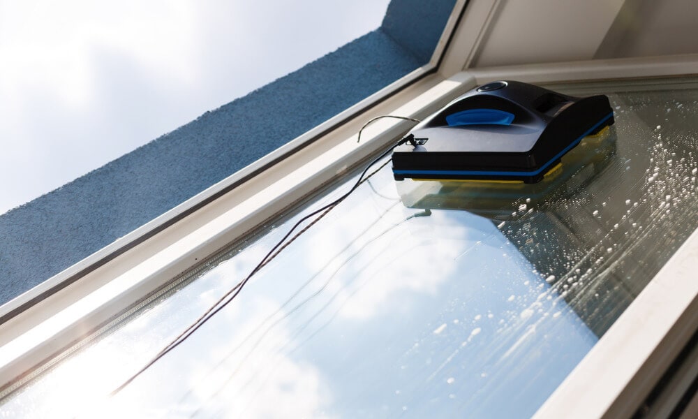 Ein Fensterputzroboter putzt eine Fensterscheibe von außen.