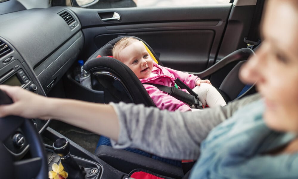 Mutter und Baby im Babyautositz fahren mit dem Auto.