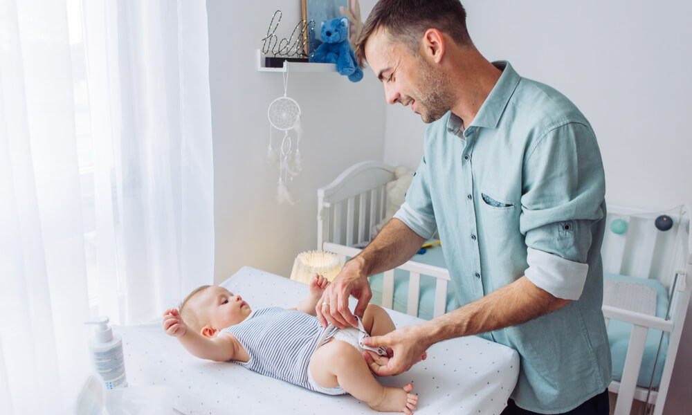 Papa wickelt sein Baby auf einem Wickeltisch.